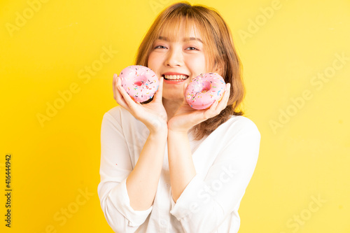 Young asian girl holding donut with cheerful expression on background