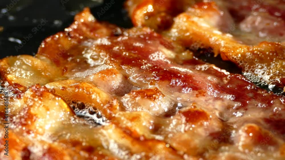 Fry the bacon in a pan. A slice of pork bacon is prepared in its own fat. Layer of meat and lard. Close up in the kitchen. Fry the bacon in a pan. A slice of pork bacon is prepared in its own fat. Layer of meat and lard. Close up in the kitchen.
