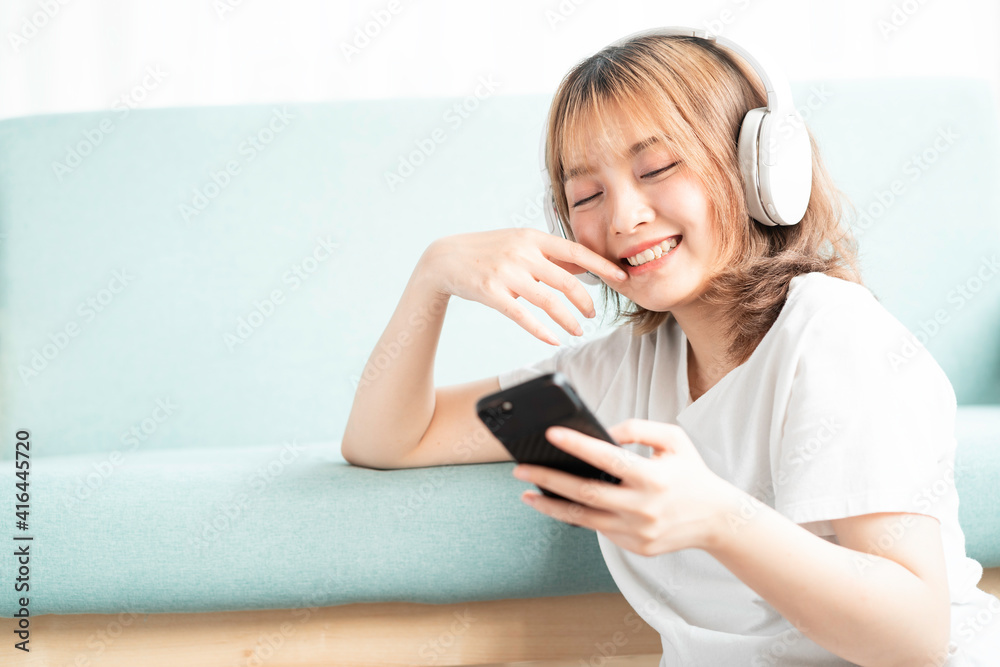 The young girl leaned against the sofa using her phone The young girl leaned against the sofa using her phone