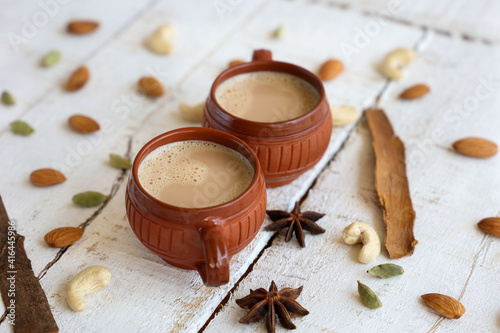 Top view of Indian herbal Masala Chai or traditional beverage tea with milk and spices Kerala India. Two cups of organic ayurvedic or herbal drink India, good in winter for immunity boosting. © sanirimpan