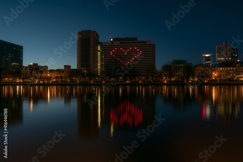 City lights heart shaped on hotel building reflected on the river covid solidarity	