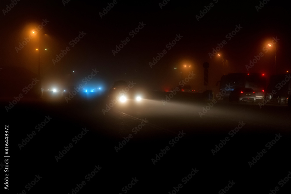 Cars white headight in the fog and yellow lantern light