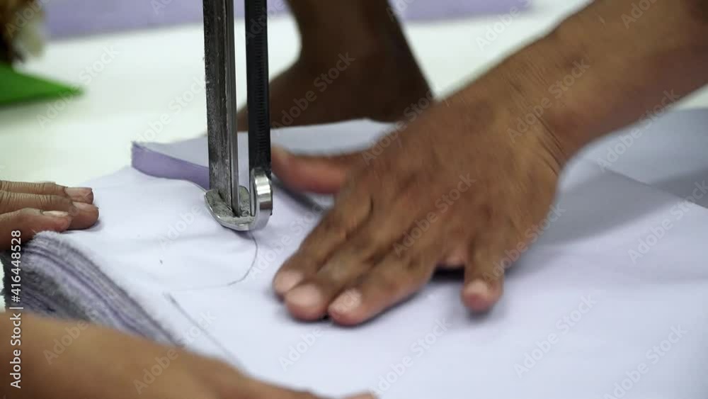 Factory worker cutting of fabric in factory. Used the razor machine for cutting fabrics in mass production.