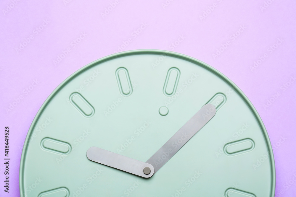 Stylish clock hanging on color wall, closeup Stylish clock hanging on color wall, closeup