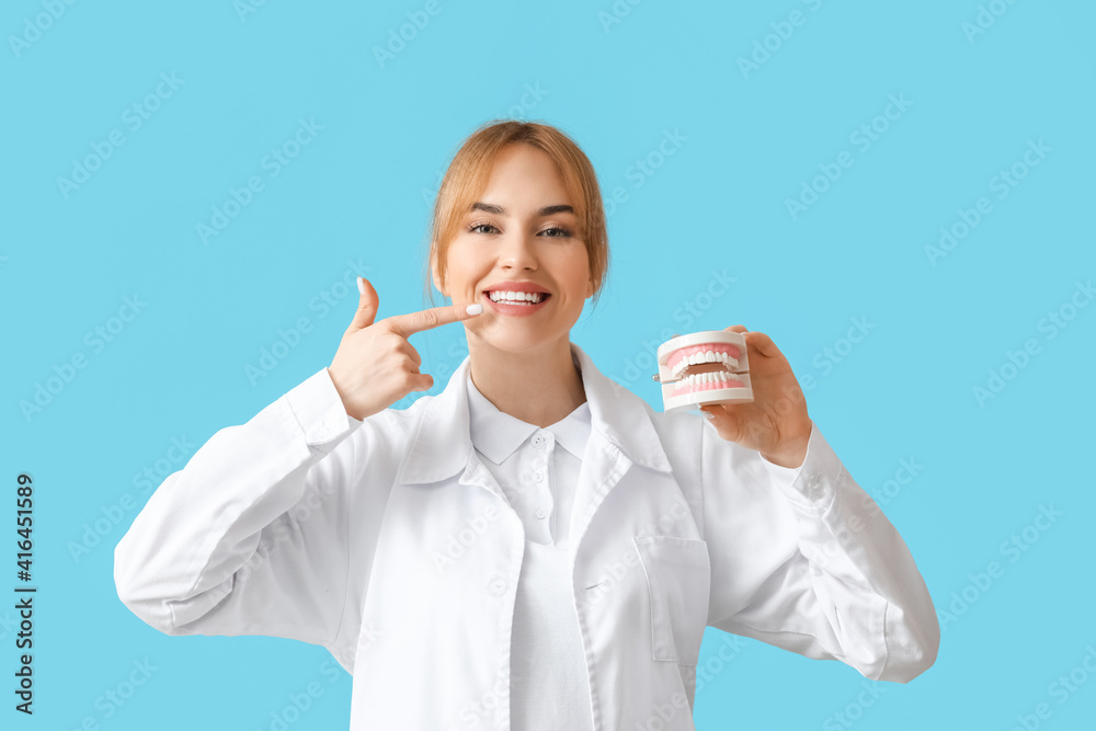 Female dentist with plastic jaw model on color background Female dentist with plastic jaw model on color background