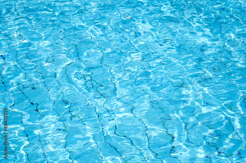 Bright blue water ripple with sparkles and water waves refraction. Abstract image from swimming pool water surface.