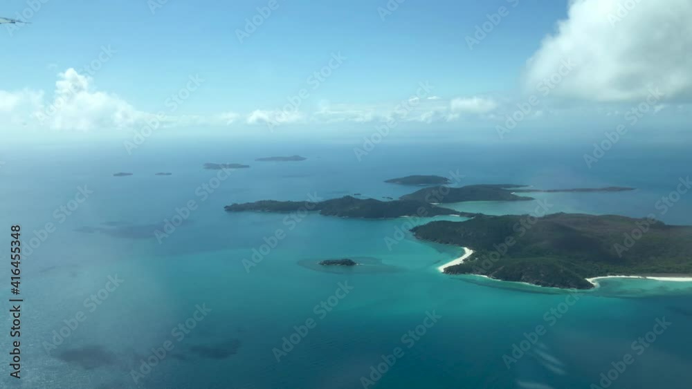 A number of islands of The Whitsunday Islands in an azure blue ocean seen from an airplane A number of islands of The Whitsunday Islands in an azure blue ocean seen from an airplane