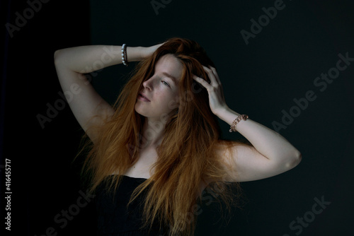 Ginger hair young white model holding her hair with black background