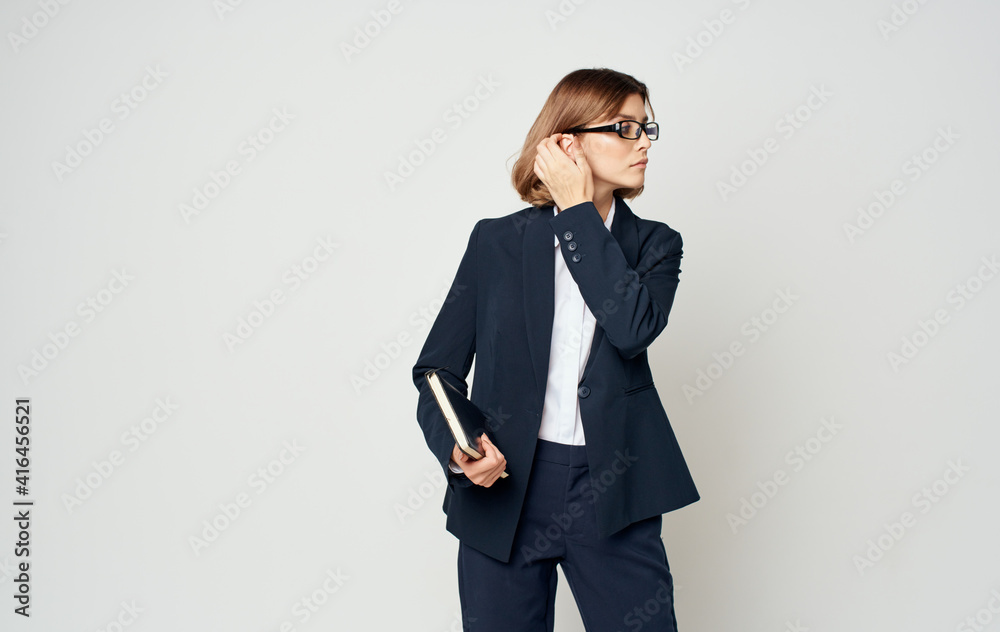 Business woman in a blue jacket and a white shirt with glasses on her face and a book in her hands Business woman in a blue jacket and a white shirt with glasses on her face and a book in her hands