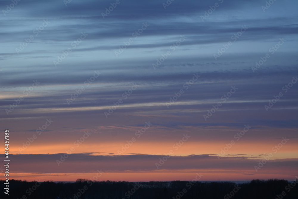Colorful sunset in winter. Striped clouds in the sky