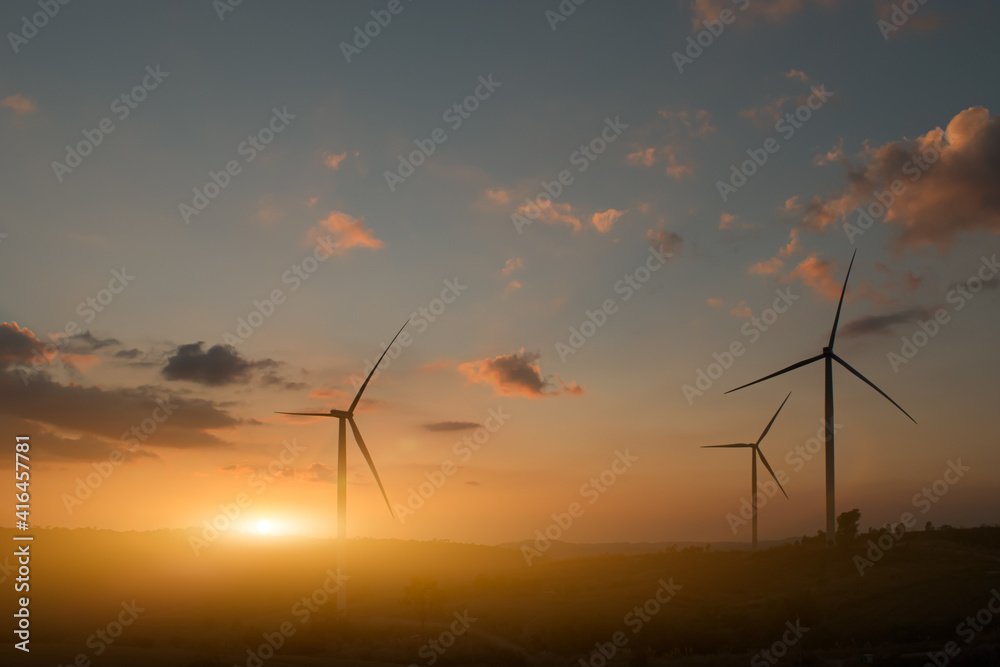 Obraz premium Silhouette of wind turbines. Beautiful view of wind generators in the mountain hill at sunset.