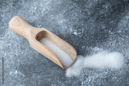 Salt in a wooden spoon on a marble background