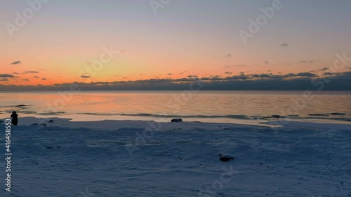 Sunset in a calm sea with frozen seashore. Shot from drone