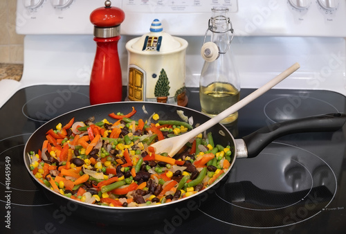 Frying pan with vegetable mix on the stove top.