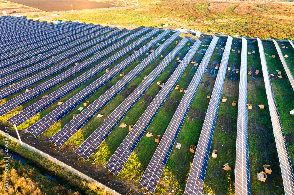 Aerial view of solar power plant under construction on green field. Assembling of electric panels for producing clean ecologic energy.