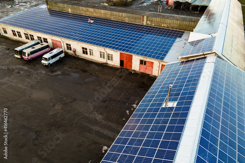 Aerial view of surface of blue photovoltaic solar panels mounted on industrial  building roof for producing clean ecological electricity. Production of renewable energy concept.