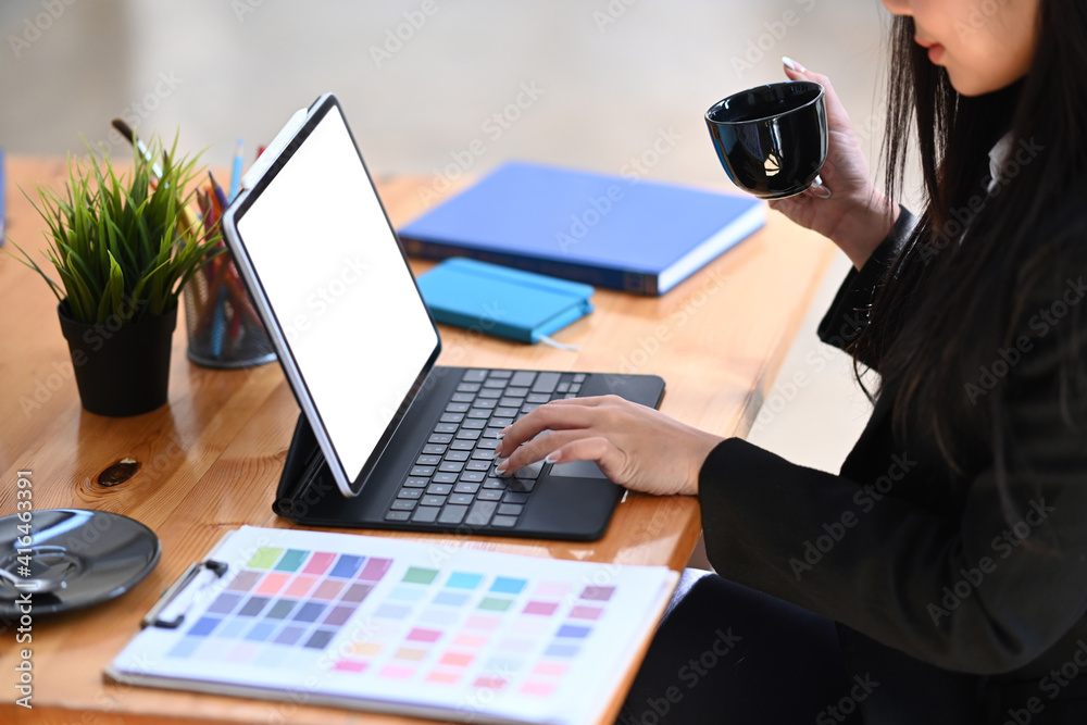 Young female graphic designer working on digital tablet and drinking hot coffee. Young female graphic designer working on digital tablet and drinking hot coffee.