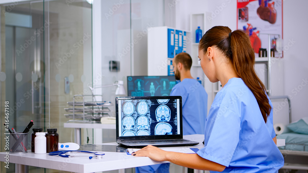 Obraz premium Assistant expertise doctor in medical uniform examining digital x-ray film and writing diagnosis on clipboard in hospital clinic, notting treatment for patient. Radiologist analysing radiography