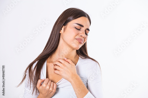 Young woman scratching her neck due to itching on a gray background. Female has an itching neck. The concept of allergy symptoms and healthcare