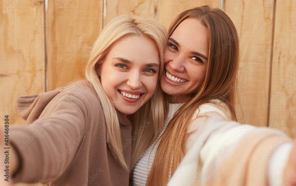 Happy girlfriends hugging and taking selfie Happy girlfriends hugging and taking selfie