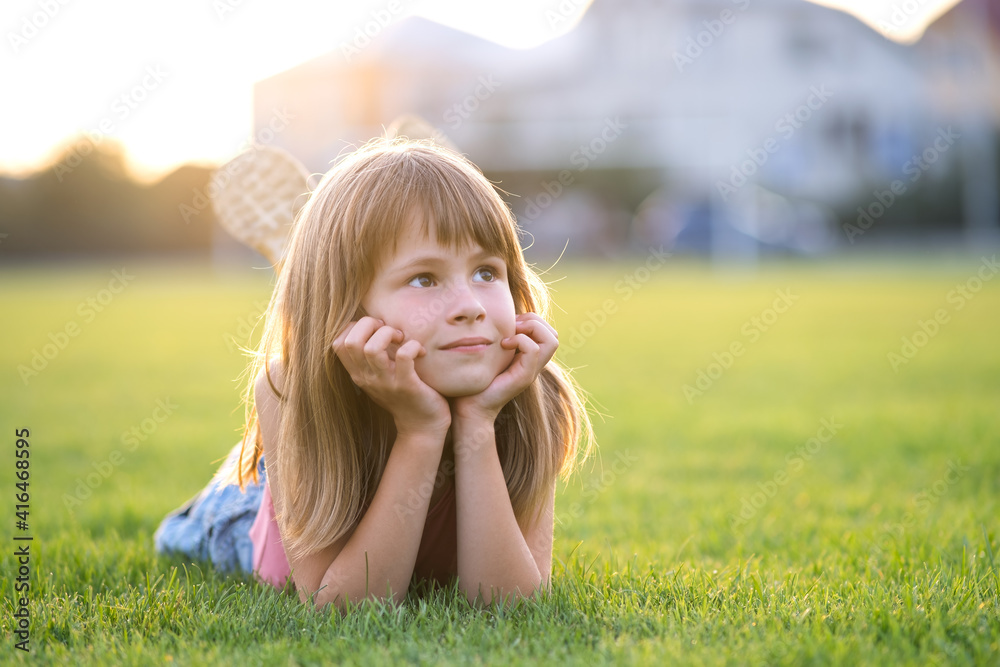 Young pretty child girl laying down on green grass lawn on warm summer day. Young pretty child girl laying down on green grass lawn on warm summer day.