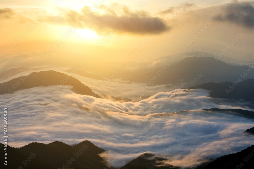 Sunset landscape with high peaks and foggy valley with thick white clouds under vibrant colorful evening sky in rocky mountains. Sunset landscape with high peaks and foggy valley with thick white clouds under vibrant colorful evening sky in rocky mountains.