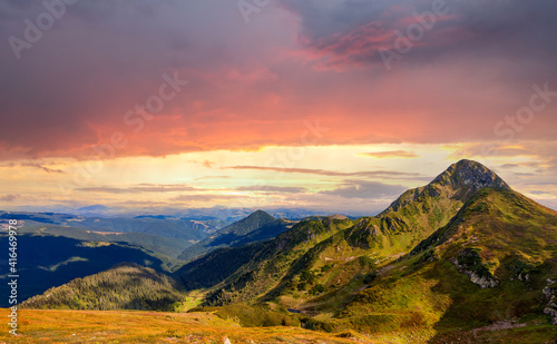 Sunset landscape of high mountain peaks under vibrant colorful evening sky.