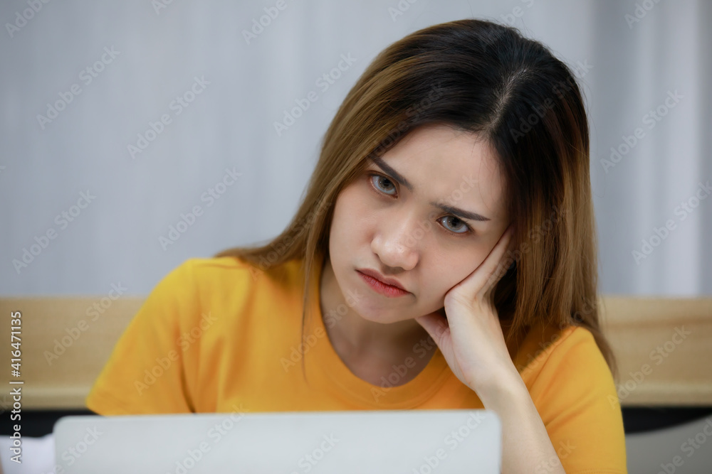 Angry bored. Asian beautiful woman wearing a Orange dress is working online on the bed in the bedroom at home. Concept Angry bore woman Not satisfied. Angry bored. Asian beautiful woman wearing a Orange dress is working online on the bed in the bedroom at home. Concept Angry bore woman Not satisfied.