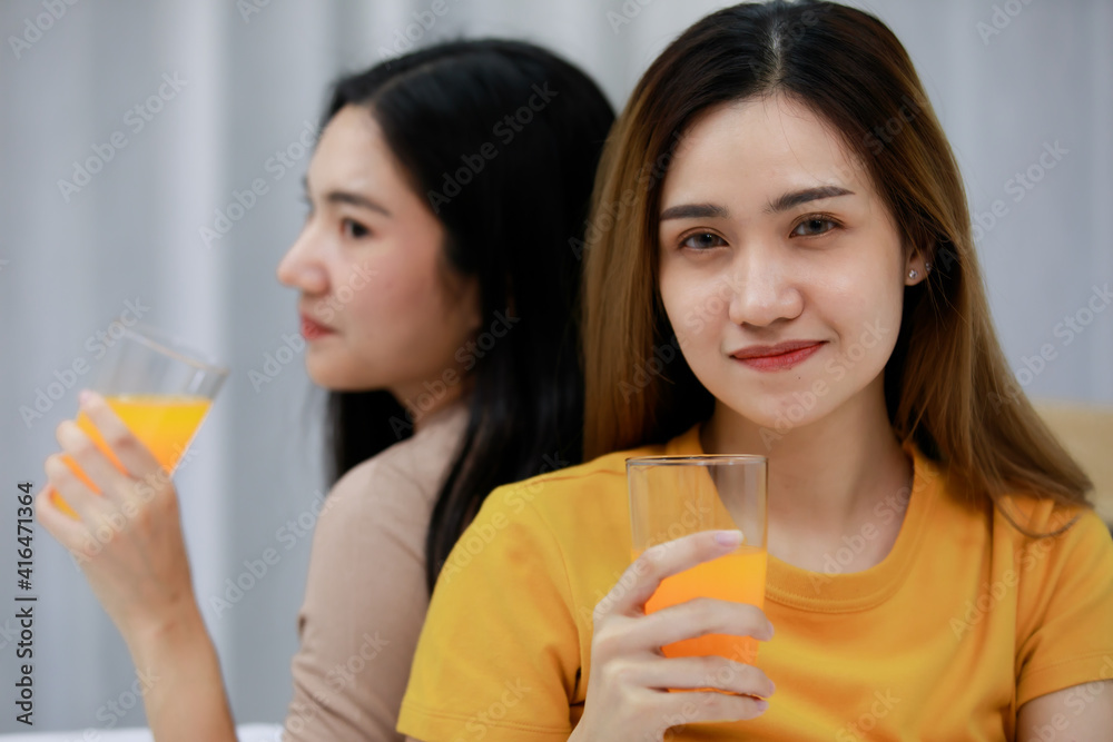 Smiling Two Asian young women looking at orange juice in the glass lovely couple on white bed. Funny women Before going to bed together on cozy. Concept In love homosexual lesbian lgbt, lgbtq, lgbtq+. Smiling Two Asian young women looking at orange juice in the glass lovely couple on white bed. Funny women Before going to bed together on cozy. Concept In love homosexual lesbian lgbt, lgbtq, lgbtq+.