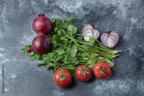 Fresh red tomatoes with greens on a marble background