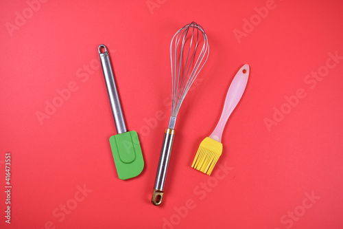 Kitchen tools for baking hand mixer spoon brush on red background