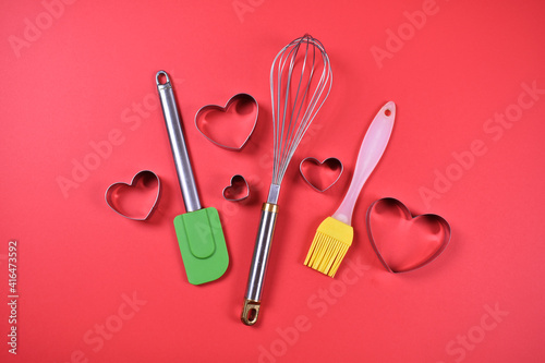Kitchen tools for baking hand mixer spoon brush heart shapped pans  on red background