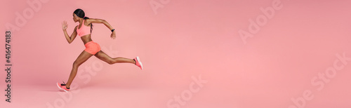 Sportswoman sprinting on a large pink background