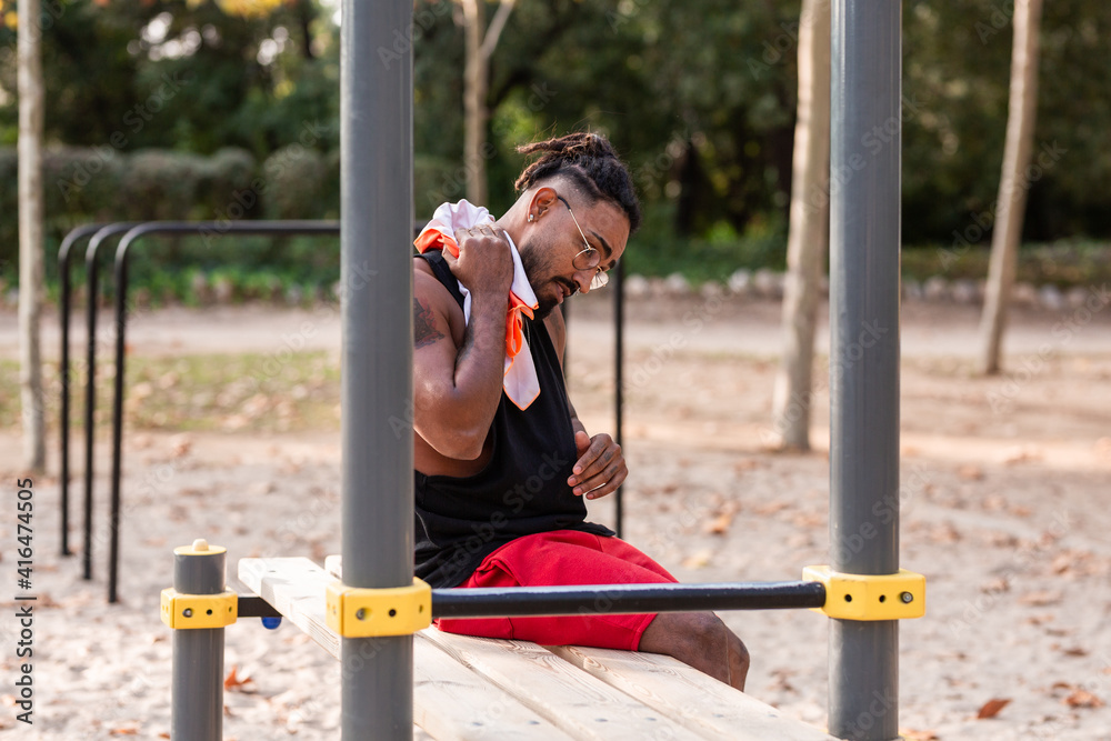 Obraz premium african-american athlete boy, rests and towels off after fitness session in park