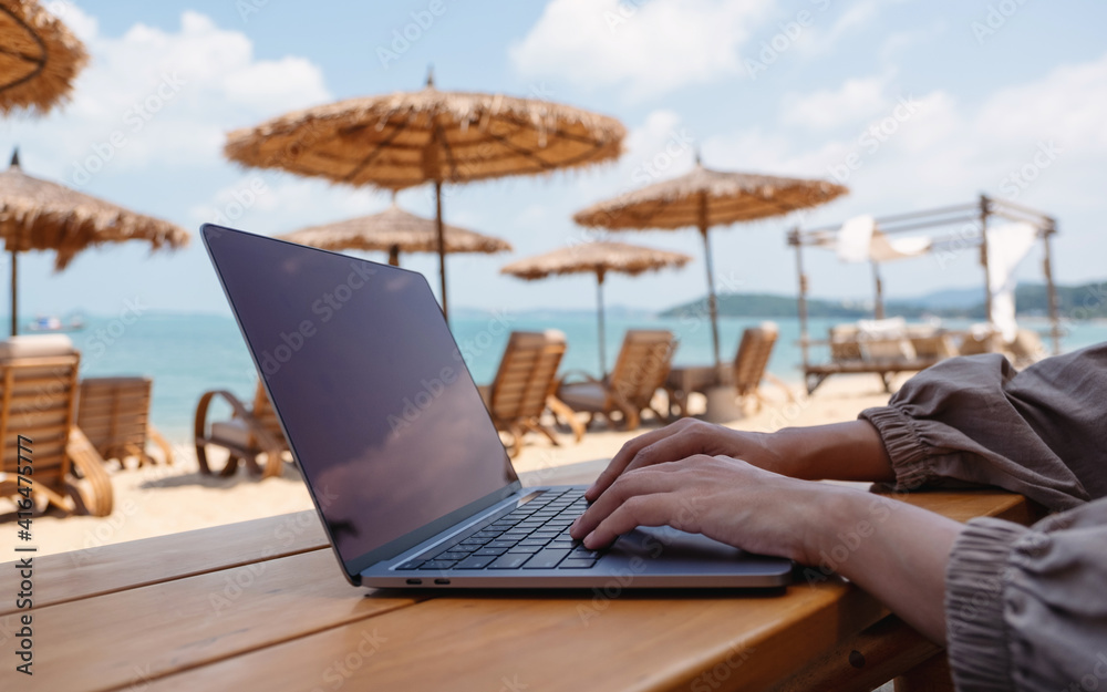 Closeup of a woman working and typing on laptop tcomputer on the beach Closeup of a woman working and typing on laptop tcomputer on the beach