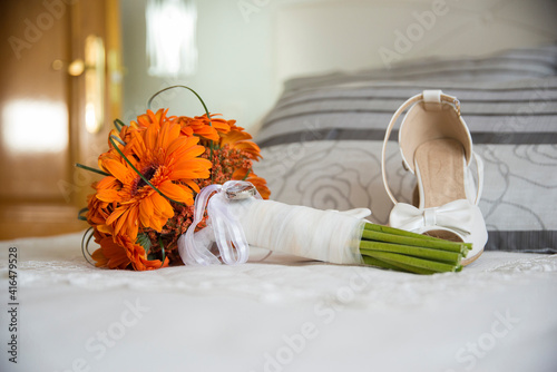 RING BOUQUET AND BRIDAL SHOES ON BED.