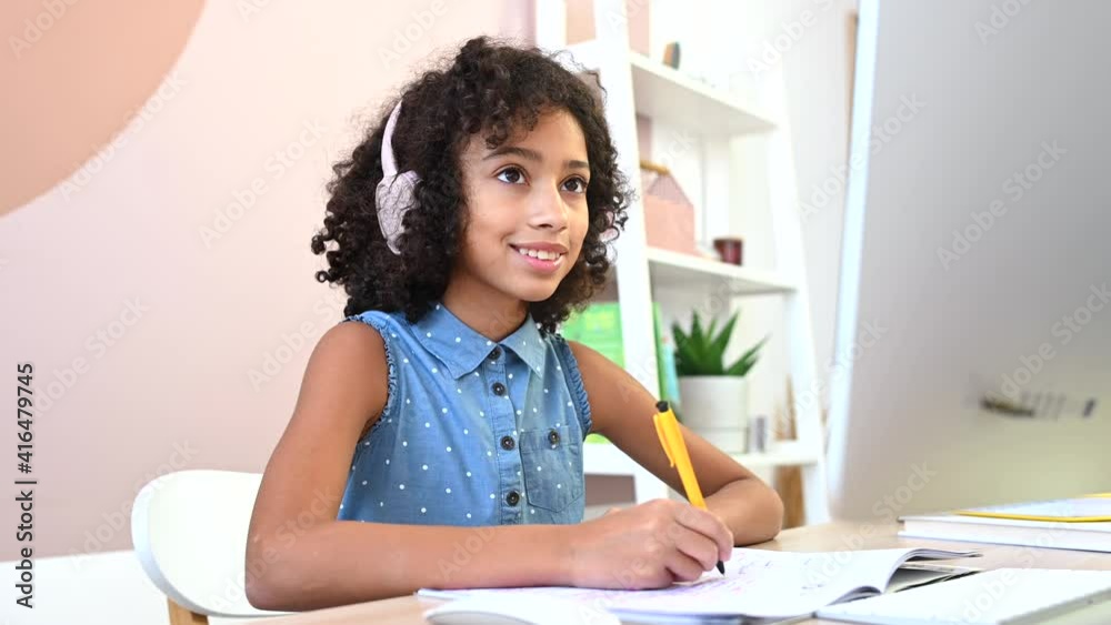 Cute African schoolgirl enjoying e-learning, looks at the camera with a cheerful smile watching online classes, tutorial on trendy PC at home, using interesting app for studying on the distance Cute African schoolgirl enjoying e-learning, looks at the camera with a cheerful smile watching online classes, tutorial on trendy PC at home, using interesting app for studying on the distance