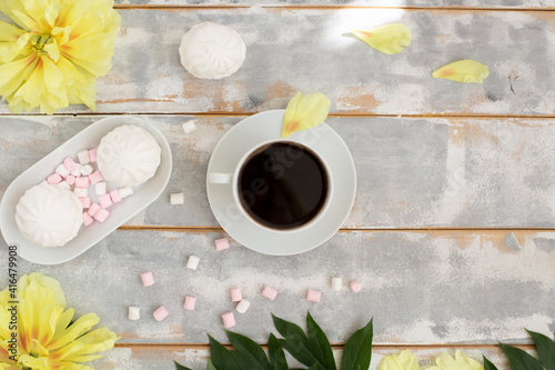 Morning coffee, marshmallows and beautiful yellow peony flowers on light table top view in flat lay style. Cozy breakfast on Mother or Woman day. photo