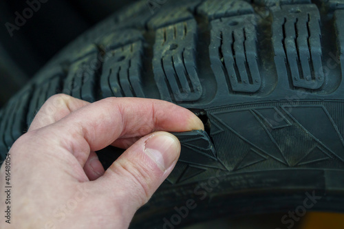 Fingers show a side rupture of a studded unrepairable winter car tire