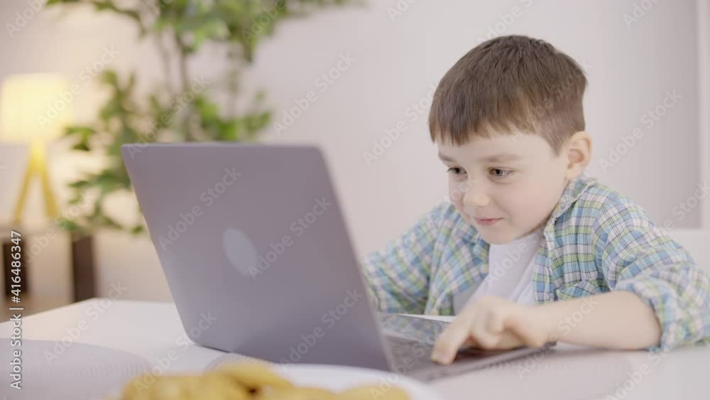 Excited caucasian boy playing computer game, sitting at the table, leisure Excited caucasian boy playing computer game, sitting at the table, leisure