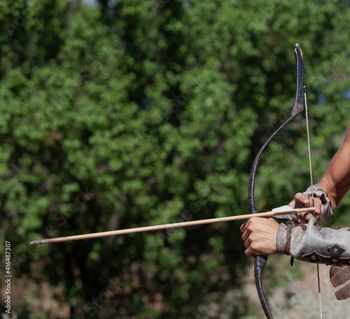 Male hands insert arrow into vintage bow