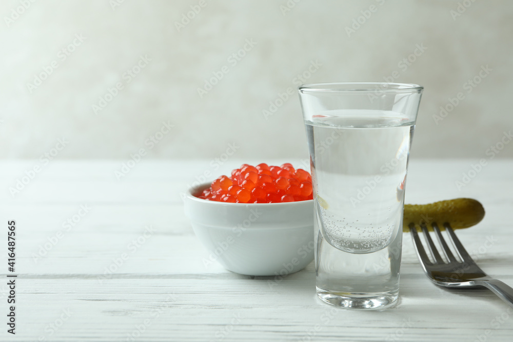 Shot of vodka, caviar and pickle on white wooden background Shot of vodka, caviar and pickle on white wooden background