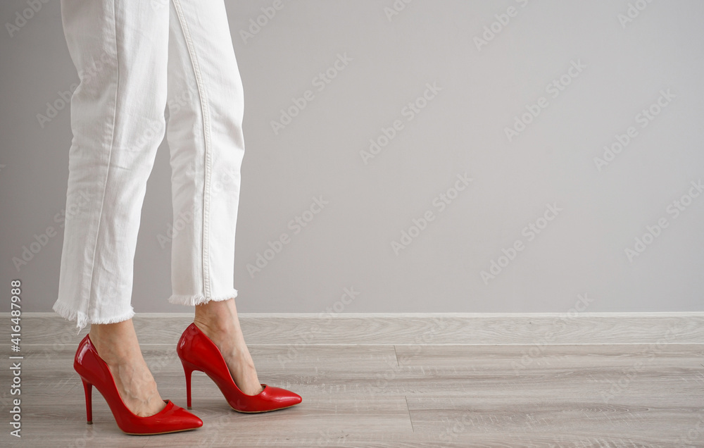 Legs of a young woman in jeans and shoes on a gray background, place for text. Legs of a young woman in jeans and shoes on a gray background, place for text.
