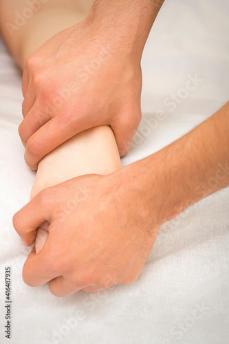 Closeup of young female receiving foot massage in two hands in a spa