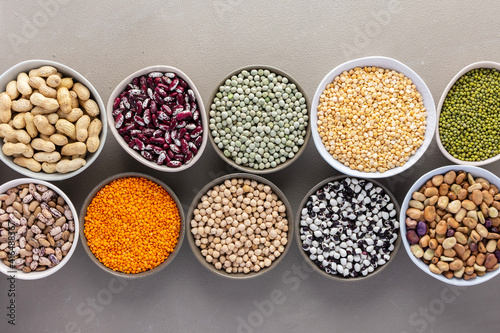 Different types of legumes in bowls, green and yellow peas, chickpeas and peanuts, colored beans and lentils, mung beans and beans, top view