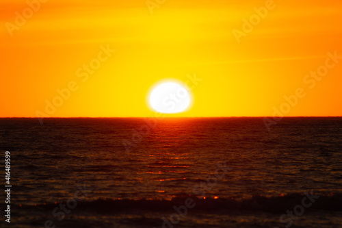 Orange sunset over the horizon turning  red cloudy sky with beautiful sea foreground