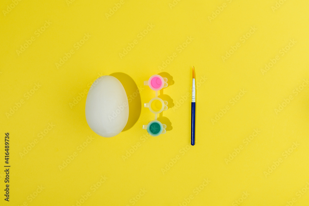 Easter egg painting set. Brush and paint on yellow background Easter egg painting set. Brush and paint on yellow background