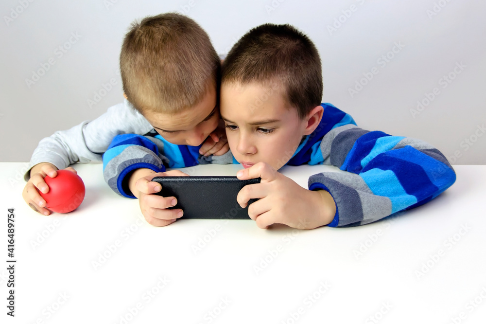Two little boys playing a game on the smartphone Two little boys playing a game on the smartphone