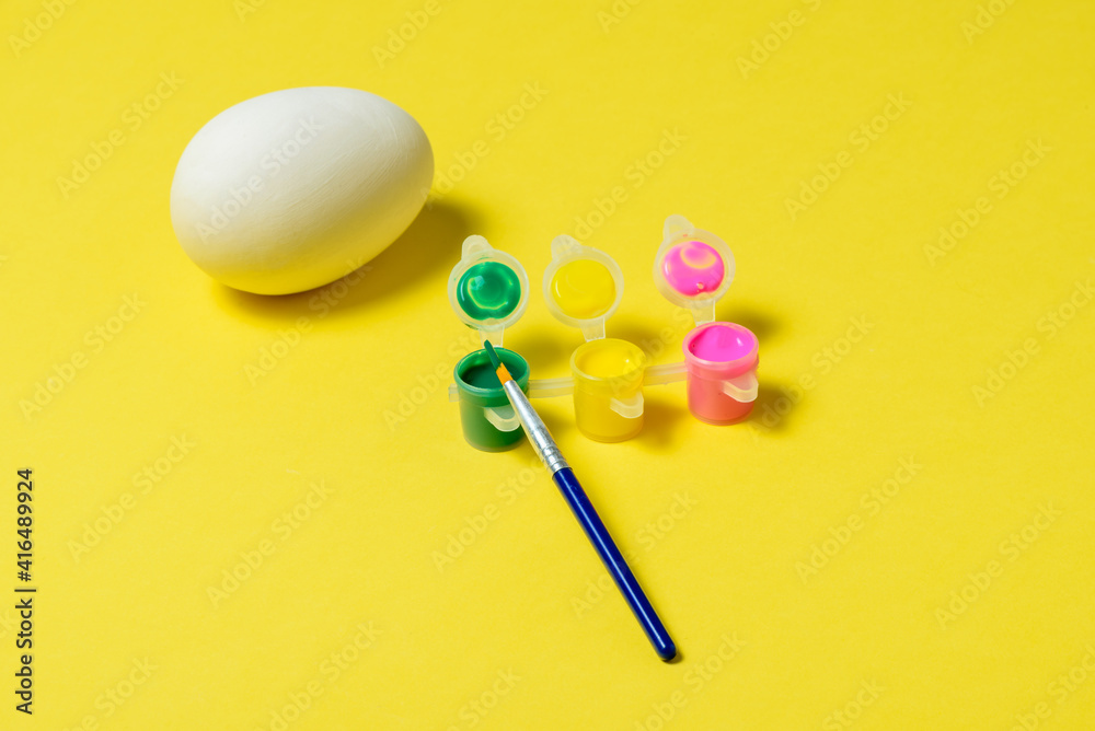 Easter egg painting set. Brush and paint on yellow background Easter egg painting set. Brush and paint on yellow background
