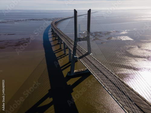 Aerial view of Vasco da Gama bridge with a few vehicles on the suspended road due the Covis-19 pandemic, view of the Tagus river, Lisbon, Portugal. © Martina